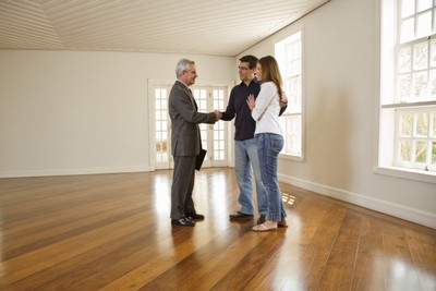 Couple shaking hands with realtor in empty room